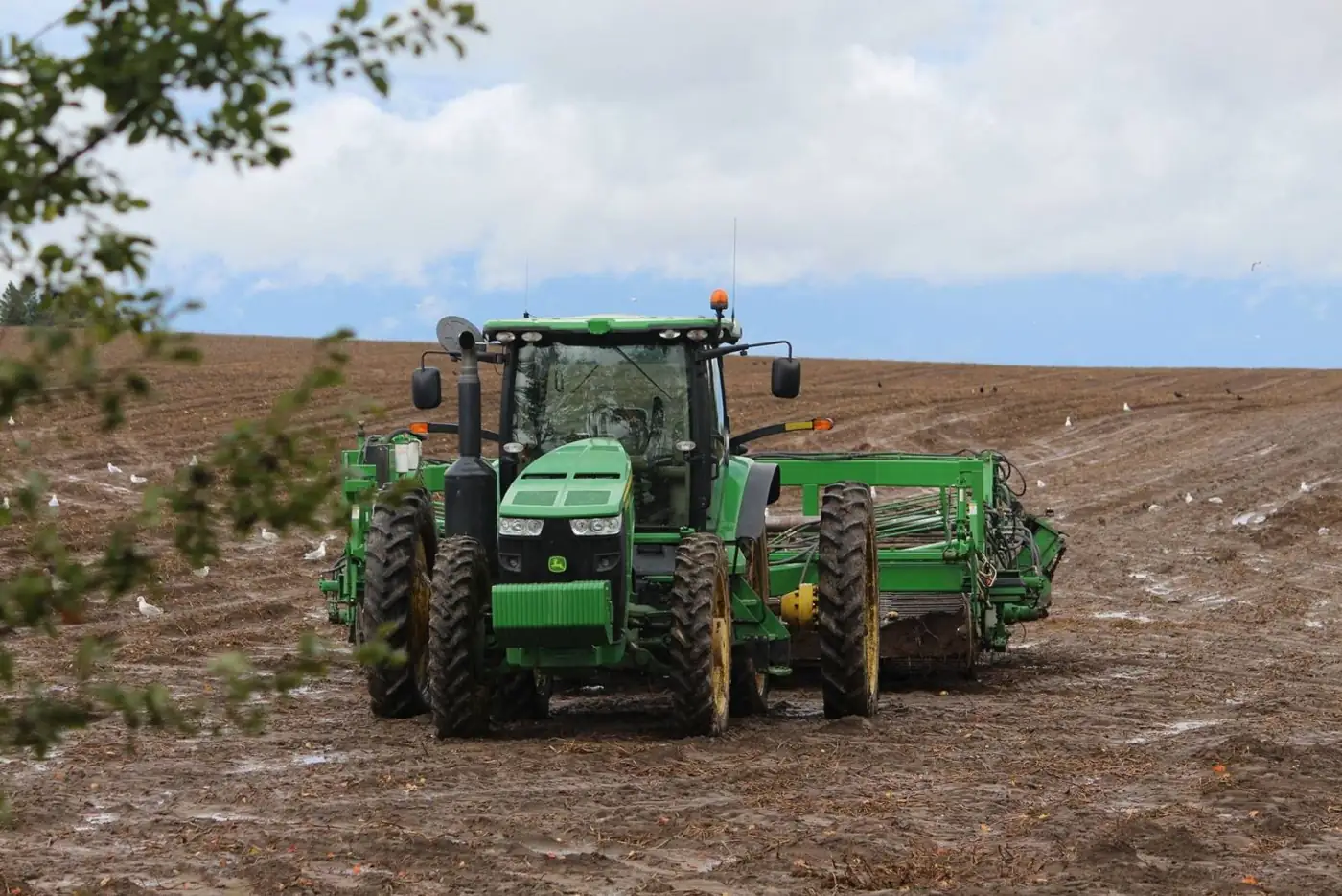 Tractor pulling an implement across a plowed field