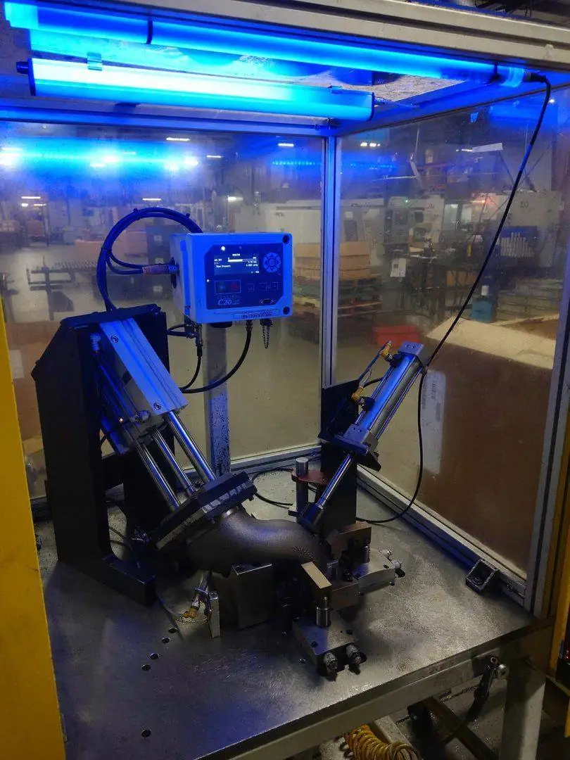 Automated leak test cell for a cast elbow
